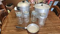 Full overview of all items including the large pot, four preserving jars, the steamer/sterilizer on left, and small frying pan in front