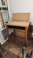 Full view of vintage solid wood school desk with visible wear and inkwell hole to the right of the writing surface