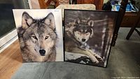 Both framed wolf prints positioned side by side on floor, showing overall condition and size.