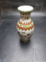 Photo showing the full view of the small vase with detailed floral and butterfly decoration and geometric pattern bands.