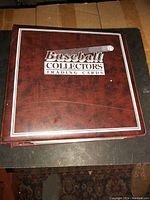 Closed maroon binder labeled 'Baseball Collectors Trading Cards' on cover, showing condition and branding of one binder in the lot.