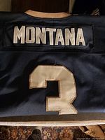 Photo of the back of the jersey showing 'MONTANA' and the number '3' in white patches on dark fabric.