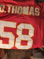 Back of the red sports jersey showing the name "D. THOMAS" and the number 58 in white with gold borders.