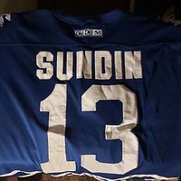 Photo showing back of the jersey with stitched name Sundin and number 13 on light blue fabric.
