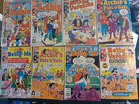 Eight Archie comic books laid out in two rows, showing colorful illustrated covers from various titles including Archie, Betty and Veronica, Betty-Me, and Archie's Pals 'n Gals from the 1980s-1990s