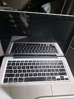 Front view of Apple MacBook laptop showing keyboard, trackpad, and display in open position.