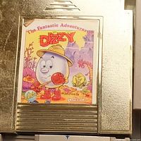 Close-up photo of a gray Nintendo game cartridge with colorful label 'The Fantastic Adventures of Dizzy' showing cartoon character and fantasy imagery.