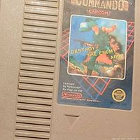 Photo of gray NES game cartridge labeled Commando by Capcom, for Nintendo Entertainment System
