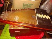 Top view of the autoharp showing strings, tuning pins, chord bars, and sound hole.