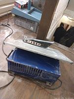 Electric tile saw with blade guard and controls on a wooden workbench, showing the tabletop and power cord.