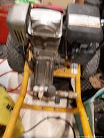 Top front angled view of the Honda pressure washer showing metal pump and gas tank, tires and frame.