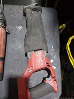 Red Milwaukee cordless reciprocating saw laying flat showing main body and handle with no battery or blade attached.