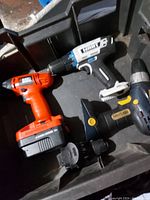 Photo showing four cordless power drivers of mixed brands and models inside a container