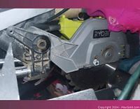 Close-up image of Ryobi table saw showing the saw blade and part of the arm with some dust and wear.