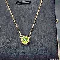 Close-up image of 18 inch 10k yellow gold necklace featuring a round faceted natural peridot stone in bezel setting.