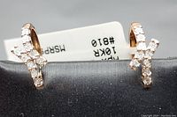 Front view of pair positioned on black stand with visible diamond X motif and white tag