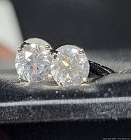 Close-up view of two round diamonds set in prong settings on fabric