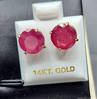 Front view of round natural ruby stud earrings on 14kt gold display card