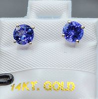 Front view of the pair of natural tanzanite round stud earrings set in 14k gold, displayed on a white textured card.