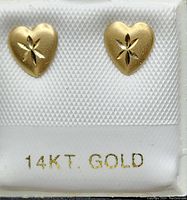 Front view of the pair of heart-shaped earrings with diamond cut star motif in yellow gold displayed on a white card.