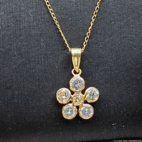 Front view of yellow gold flower pendant with six round diamonds.