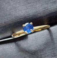 Close-up of the ring showing the sapphire gemstone and gold band from a side angle.