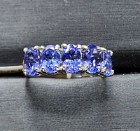 Top view showing five oval violet-blue tanzanite stones set in prong settings on white gold band
