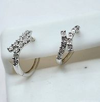 Pair of earrings on white display tube showing crossover diamond detail