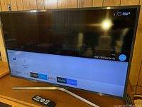 Samsung 40-inch Smart TV powered on showing smart TV interface with apps and CBS Sports HQ channel and curved silver stand