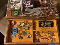 Wide top view of vintage men's tie pins, cufflinks and other small items in a wooden jewelry box