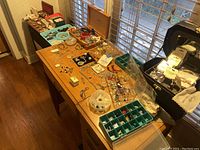 Wide view of wooden desk top with trays, boxes and loose jewelry pieces