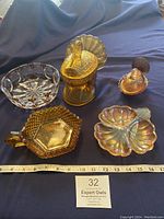 Photo of all five vintage glass candy dishes including amber turkey and dove shapes, clear crystal bowl, diamond point amber dish, and iridescent amber trinket dish on blue fabric with measuring tape.