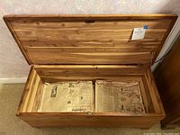 Open cedar chest showing vintage newspapers from 1926 inside and cedar chip lining.