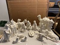 17-piece vintage porcelain nativity scene displayed on a table. Includes camel, donkey, sheep, cow, three wise men, shepherds, Mary, Joseph, and baby Jesus. All pieces have a high gloss white finish.