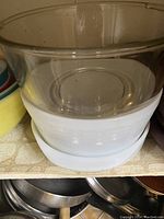 Close-up of large white ribbed glass mixing bowl with clear glass bowl inside, and colored mixing bowls stacked together