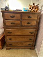 Front view of wood dresser showing all seven drawers and decorative metal handles.