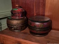 Photo showing two Asian-style decorative boxes on wooden surface, highlighting shape and design of each box.