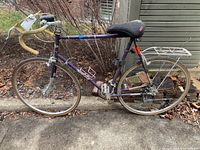 Full left side view showing purple frame, wheels, handlebar, saddle, and rear rack.