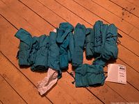 Eleven teal cloth rolls laid out on wood floor