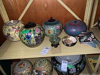 Overview of shelf with six ginger jars, two small bowls and porcelain shoe figurines