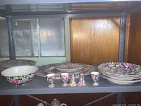 Full overview of the dish set including plates, serving bowl, egg cups, and platters on a metal shelf.