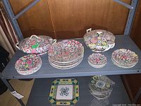 Overview of top shelf: primary floral porcelain pieces; bottom shelf: secondary design items