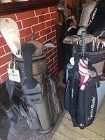 Photo showing two golf bags side by side, one brown and one black TaylorMade, with various golf clubs and headcover.