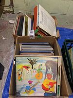 Two cardboard boxes filled with upright vinyl LP records showing assorted cover art