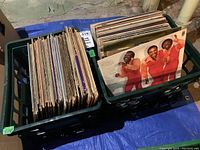 Two milk crates filled with vinyl LP records, showing the sides of records packed vertically with visible aging on covers.