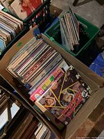 Cardboard box filled with vinyl LP records showing assorted sleeves