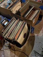 Two cardboard boxes filled with vinyl LPs on a basement floor