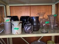 Shelf with a variety of pottery and clear glass vases and bowls showing the full lot