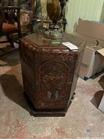 Front side of hexagonal wooden side table showing floral painted designs and multiple compartments
