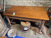 Full view of rectangular hardwood table with turned legs and visible scratches and cracks on the surface.